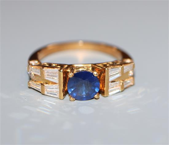 A modern 750 yellow metal, single stone sapphire dress ring, flanked with round and trapeze cut diamonds, size O.